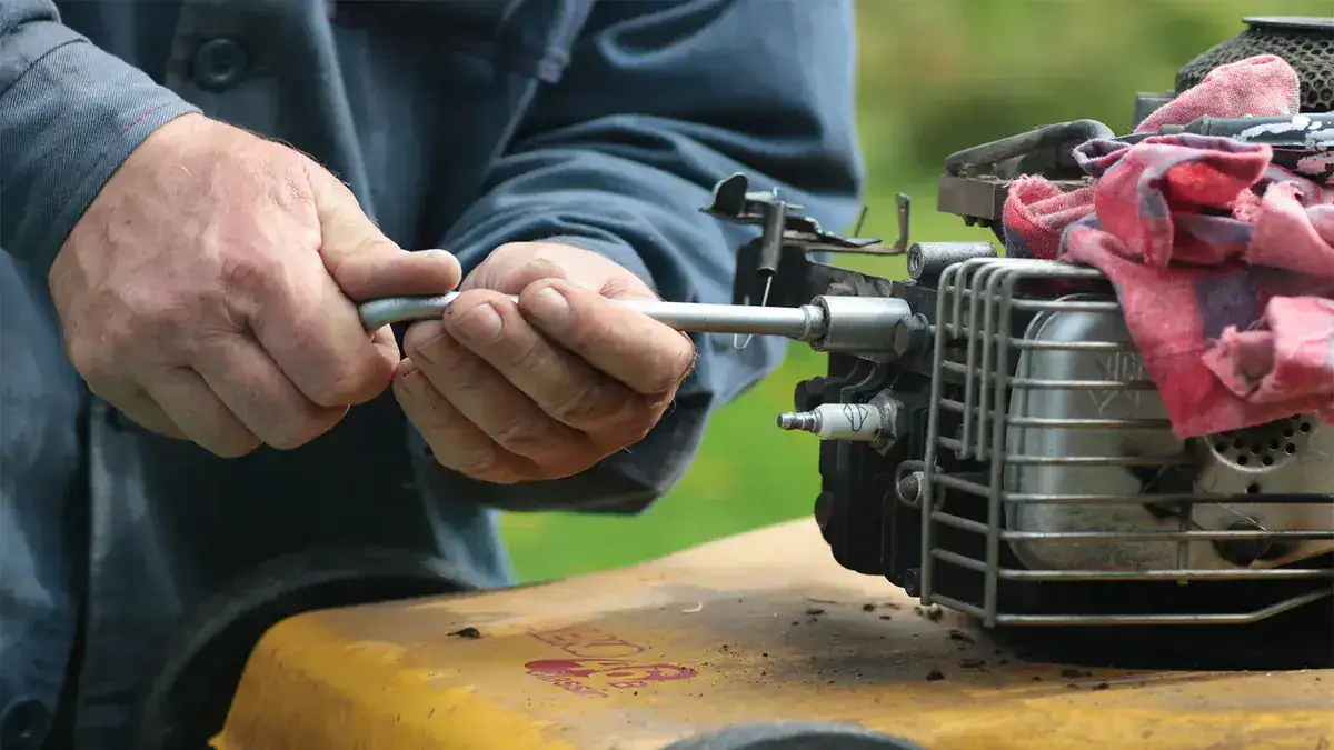 Hands working on a small engine carburetor